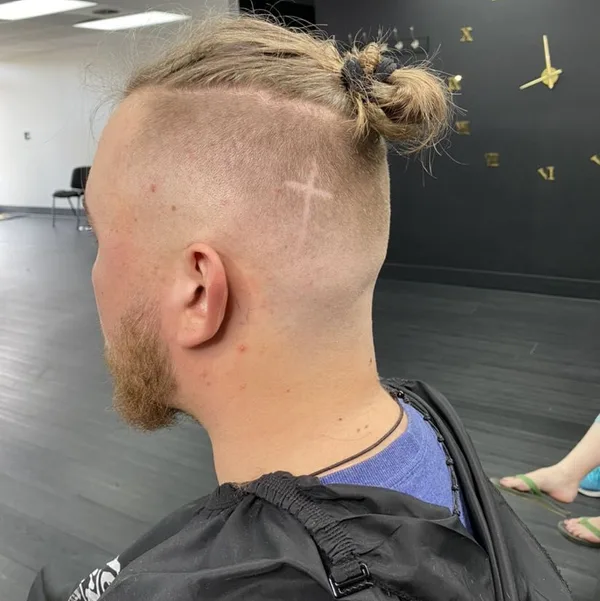 Top knot with a shaved fade and cross design at Status A Studio