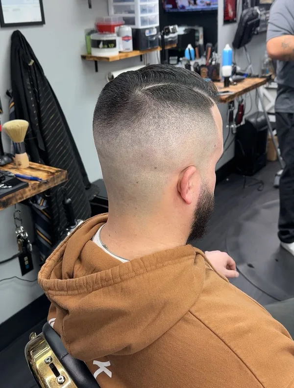 Hard part with a high bald fade and shaped beard